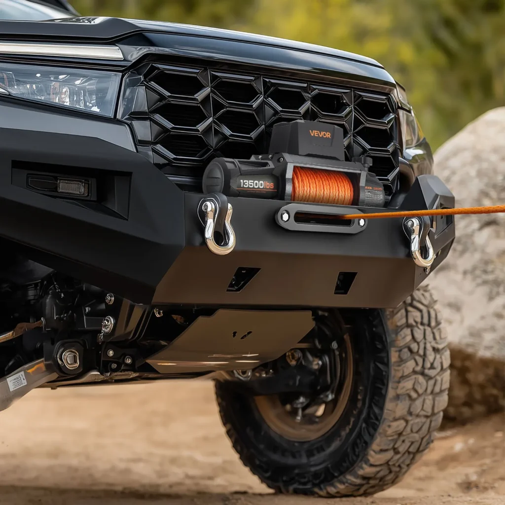 Treuil électrique Vevor 13500 lbs IP67 monté sur le pare-chocs avant d'un pick-up noir en terrain rocheux, corde synthétique orange en traction