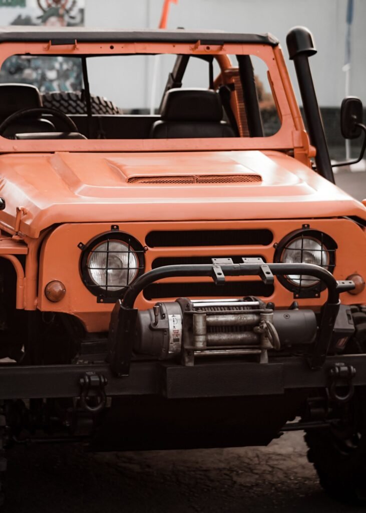 4x4 orange avec un treuil électrique fixé sur une platine dans le pare-chocs avant