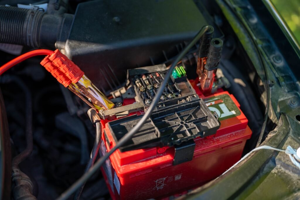 Batterie 12 V dans un compartiment moteur, câbles de démarrage branchés sur les bornes