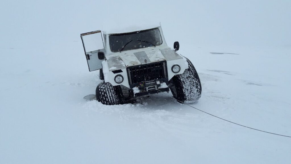4x4 blanc enlisé dans la neige profonde, la ligne de son treuil tendue vers l'avant